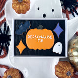 Halloween-themed biscuit set with 'Personalise Me' text in a box, surrounded by decorative pumpkins and spider biscuits.