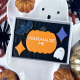 Halloween-themed cookie with 'Personalise Me' text on a decorative pumpkin biscuit surrounded by mini halloween biscuits.