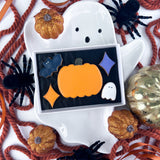 Halloween-themed cookies in a ghost-shaped cookie jar with decorative pumpkins and spiders.