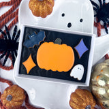 Halloween-themed biscuits in a box with decorative pumpkins and spiders around.