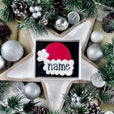 Decorative Christmas scene with a cookie featuring a personalised Santa hat, surrounded by festive elements.