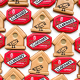 A close-up flat lay of decorated cookies shaped like Claridge's London signboards and birdhouses, arranged on a white background for Claridg'es 2025 Christmas tree celebrations.