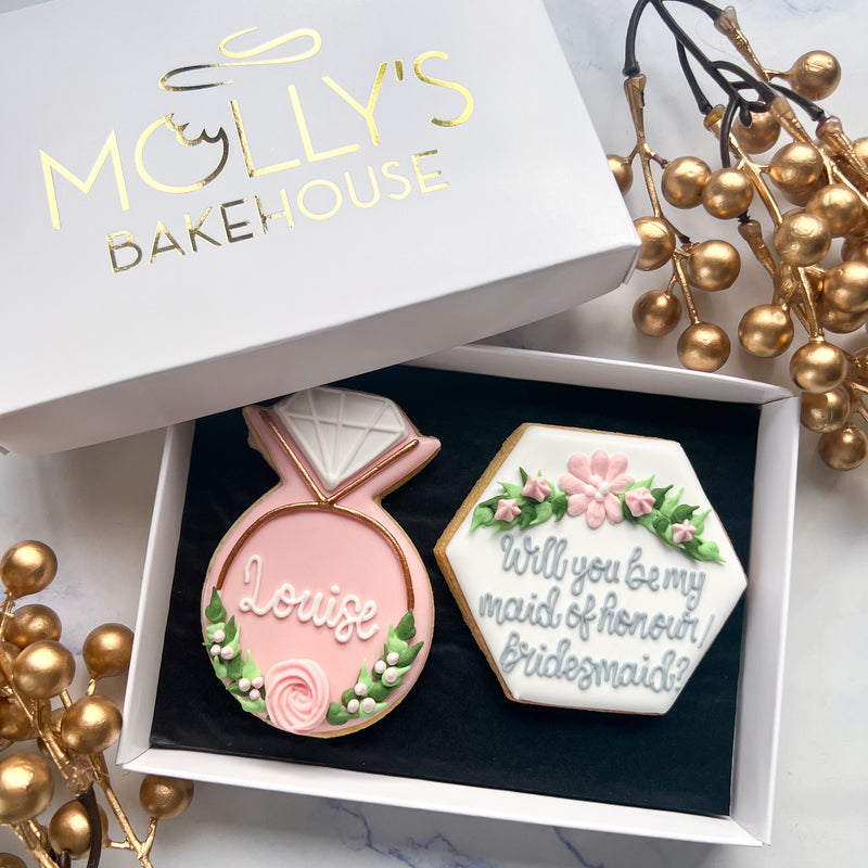 Our bridesmaid biscuit gift box comprising of a pink, floral ring & paired with a hexagonal "Will you be my bridesmaid?" biscuit with a white iced background